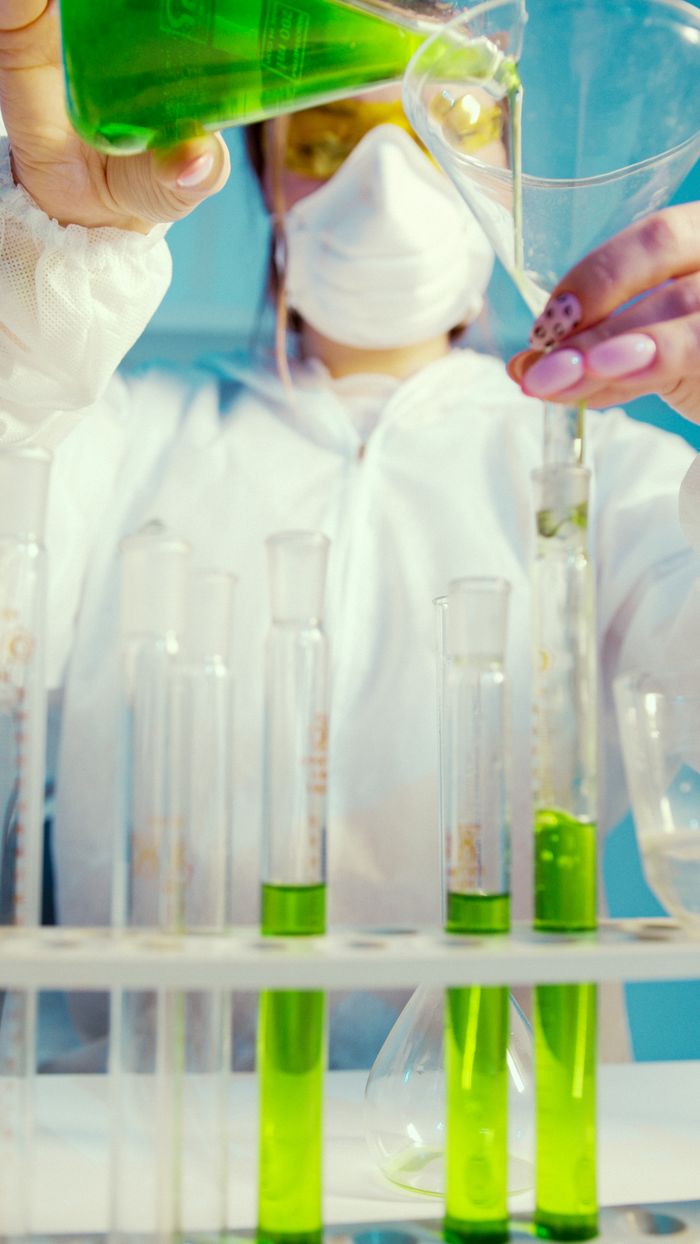 category-03 Female scientist conducting an experiment in a lab with green liquid in test tubes.